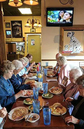 Group of elderly people sitting around a table eating dinner